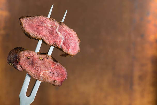 sliced steaks impaled on meat fork - Zdjęcie, obraz