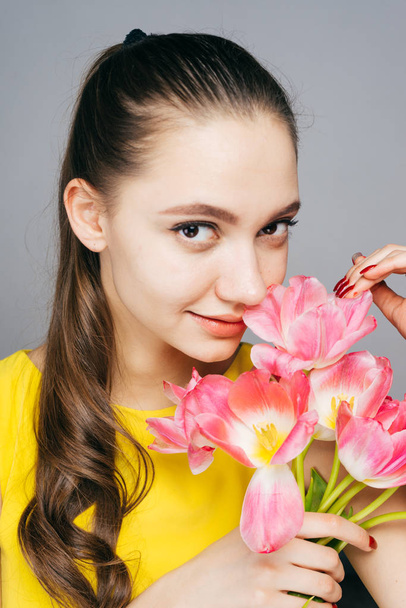 attractive beautiful girl in yellow dress holds a bouquet of fragrant pink flowers, smiling and looking at the camera - Foto, Bild