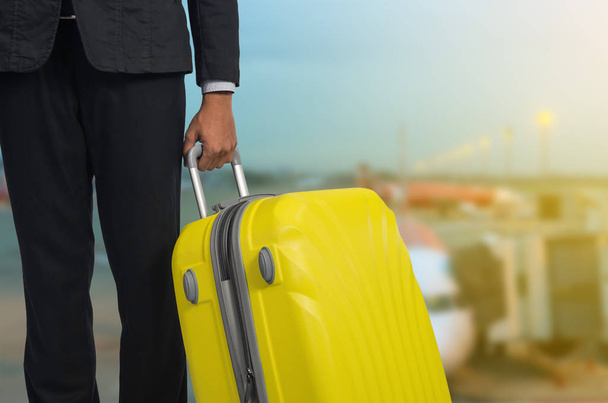 Businessman and suitcase in the airport departure lounge, airplane in the blurred background, summer vacation concept, traveler suitcases in airport terminal waiting area. . - Photo, Image
