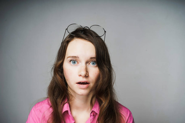 young blue-eyed woman worker in a pink shirt looks surprised at the camera - Фото, зображення