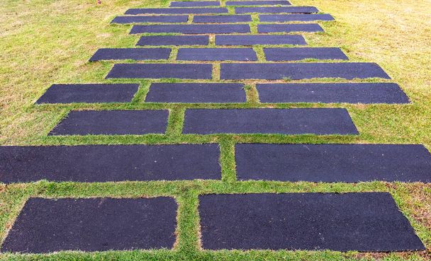 Каменная дорожка для прогулок в парке на фоне зеленой травы - Фото, изображение