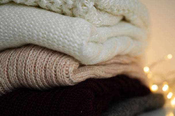Suéteres calientes. Montón de prendas de punto sobre fondo cálido, suéteres, prendas de punto, espacio para el texto, concepto de otoño invierno. Copiar espacio
 - Foto, imagen