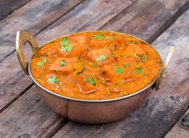 La deliciosa cocina india Paneer Tikka Masala también llamada Paneer Butter Masala es un plato indio de queso Paneer marinado servido en salsa especiada sobre fondo de madera.
 - Foto, imagen