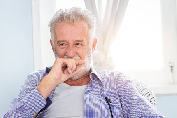 Elderly old man cute hiding smile look shy sitting in room with window. - Photo, Image