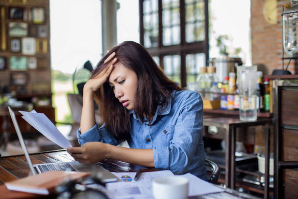 Νεαρή γυναίκα που κάθεται σε μια καφετέρια με το laptop, Stressful για εργασία. - Φωτογραφία, εικόνα