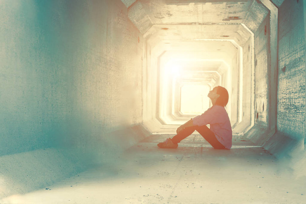 achtergrondverlichting van een tiener depressief zit in een vuile tunnel  - Foto, afbeelding
