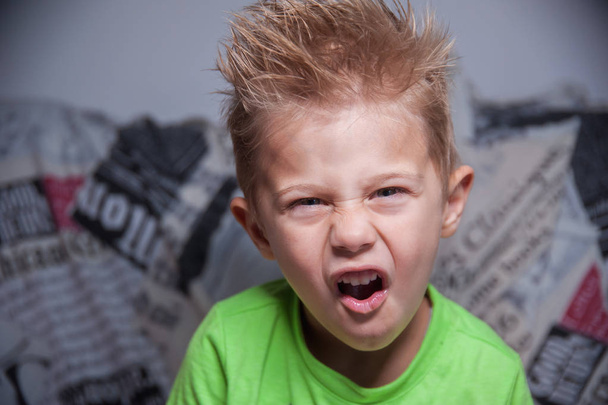 kind met een boos gezicht expressie, blond haar met gel - Foto, afbeelding