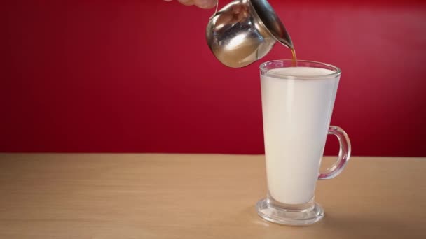 バリスタ カフェでラテを準備するためのミルクのガラスのカップにコーヒーを注ぐ - 映像、動画