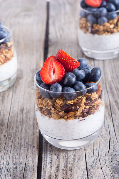 Chia yogurt with granola and berries  ( blueberries , strawberry ) in glass - Fotoğraf, Görsel