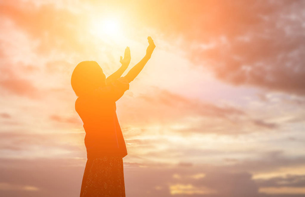 Силуэт женщины, молящейся на прекрасном фоне неба - Фото, изображение