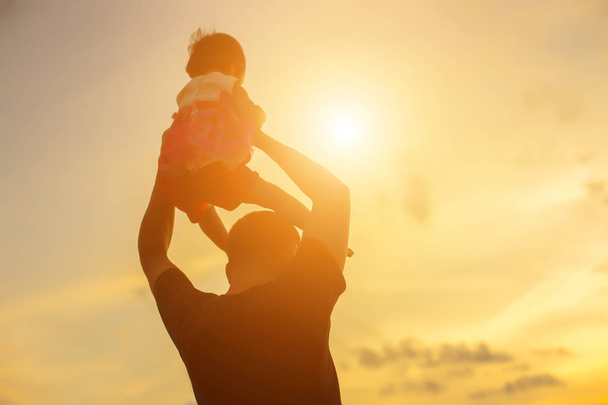 Father took the baby learn to walk at sunset. - Photo, Image