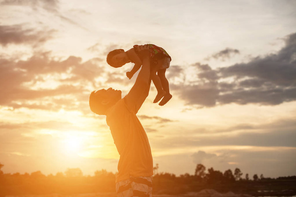 Ο πατέρας πήρε το μωρό, έμαθε να περπατάει το ηλιοβασίλεμα.. - Φωτογραφία, εικόνα