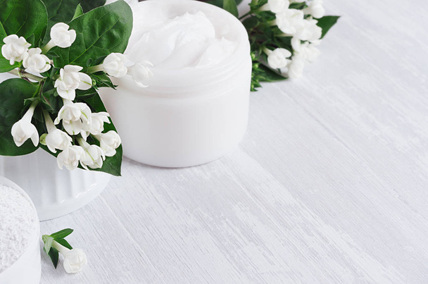 Fresh spring organic spa cosmetics products with small white flowers and green leaves on white wood background, copy space, closeup. - Фото, изображение