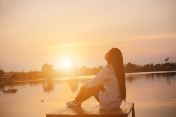 Silhouet van het mooie meisje in de natuur bij zonsondergang zomer. - Foto, afbeelding
