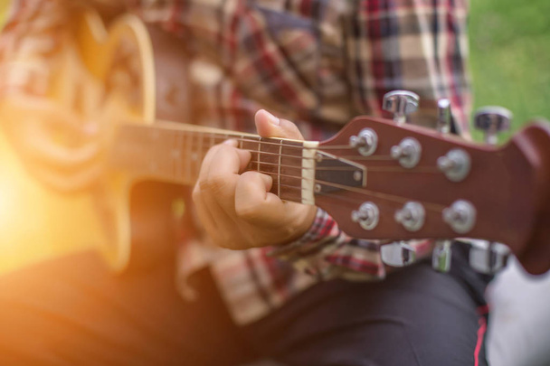 Nuori hipster mies soittaa kitaraa rentouttava hänen loma, nauttia luonnon ja raitista ilmaa
. - Valokuva, kuva