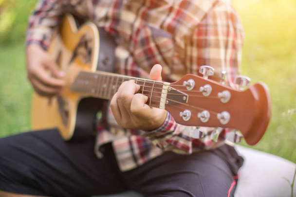 Young hipster man playing guitar to relaxing on his holiday, enjoy with natural and fresh air. - Foto, Imagen