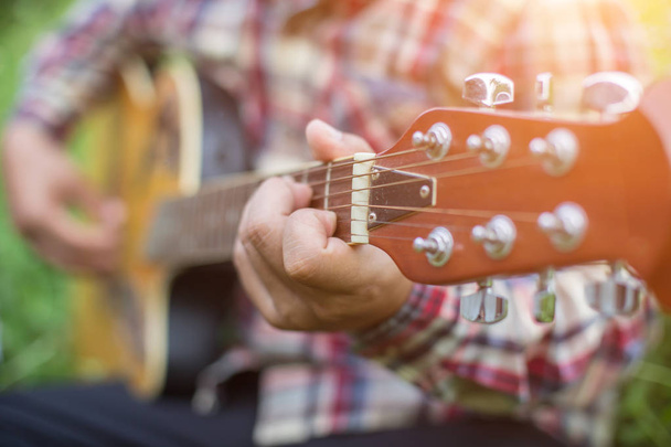 Nuori hipster mies soittaa kitaraa rentouttava hänen loma, nauttia luonnon ja raitista ilmaa
. - Valokuva, kuva