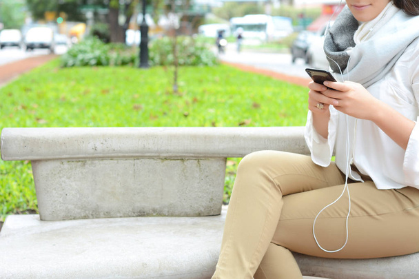красивая молодая женщина отправляет сообщение со смартфоном на улицу
. - Фото, изображение