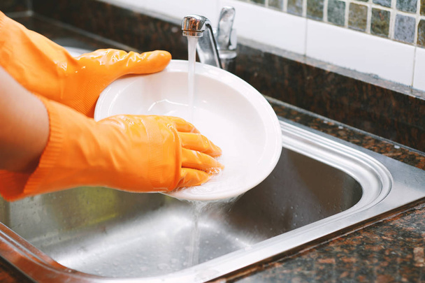 Vue rapprochée des mains dans des gants en caoutchouc qui lavent la vaisselle avec une éponge. Concept de travaux ménagers
 - Photo, image
