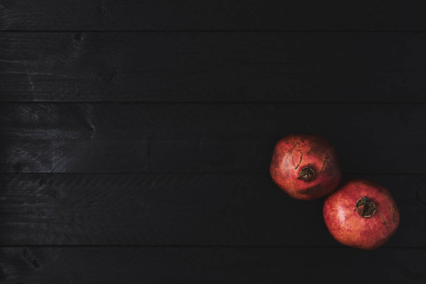 Flat lay of ripe pomegranate fruit on black wooden vintage background. Top view with copy space. - Foto, Imagen
