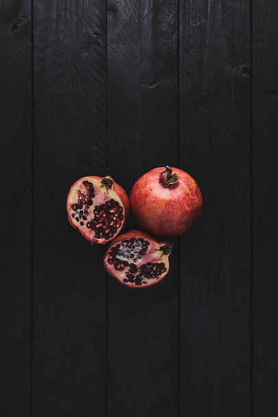 Flat lay of ripe pomegranate fruit on black wooden vintage background. Top view with copy space. - 写真・画像