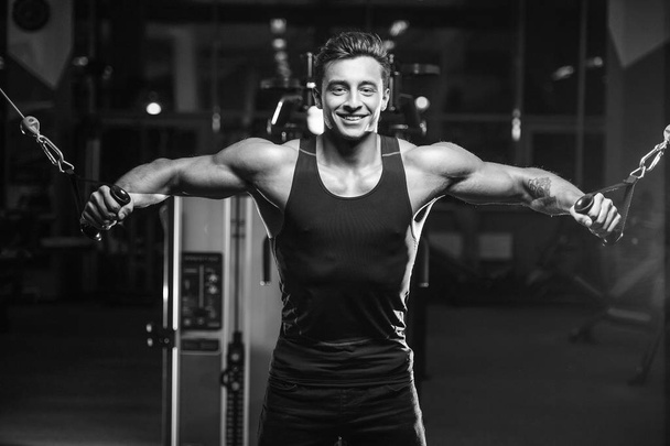 Handsome young fit muscular caucasian man of model appearance workout training in the gym gaining weight pumping up muscles and poses fitness and bodybuilding sport concept - 写真・画像