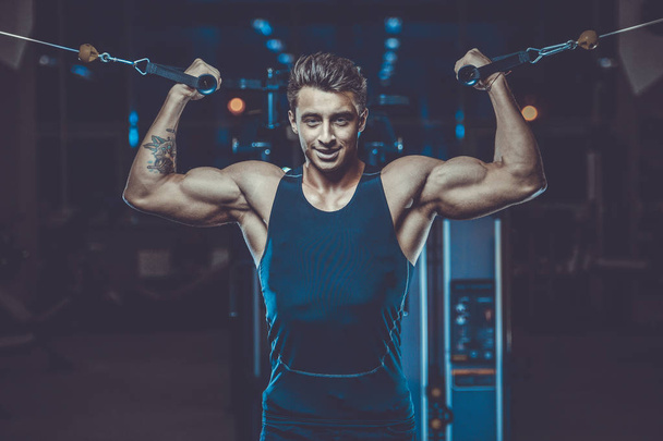 Handsome young fit muscular caucasian man of model appearance workout training in the gym gaining weight pumping up muscles and poses fitness and bodybuilding sport concept - Photo, Image