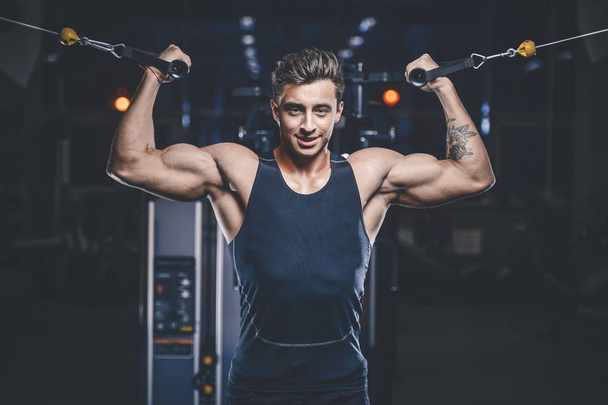 Handsome young fit muscular caucasian man of model appearance workout training in the gym gaining weight pumping up muscles and poses fitness and bodybuilding sport concept - Foto, afbeelding