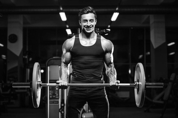 Handsome young fit muscular caucasian man of model appearance workout training in the gym gaining weight pumping up muscles and poses fitness and bodybuilding sport concept - Photo, image
