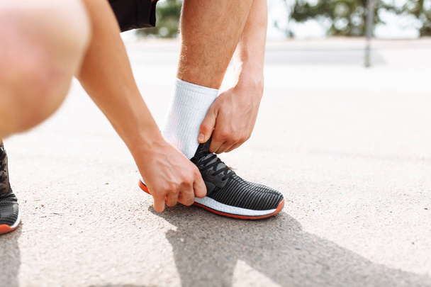 Urheilija sitoo kengännauhat kyykkyyn, lähikuva, aamuharjoittelu miehen kanssa, lepo ennen harjoittelua
 - Valokuva, kuva