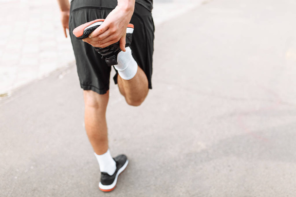 Un hombre haciendo un estiramiento de pierna antes de correr, entrenamiento matutino
 - Foto, imagen