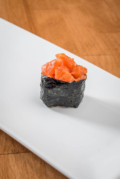 gunkan con salmón en un plato blanco sobre un fondo cálido. Sushi tradicional japonés
 - Foto, imagen