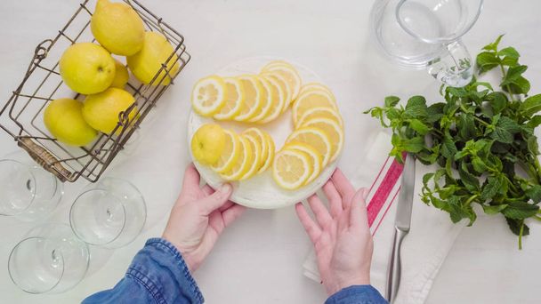 Step by step. Slicing fresh organic lemons on a white wood cutting board. - Foto, Imagen