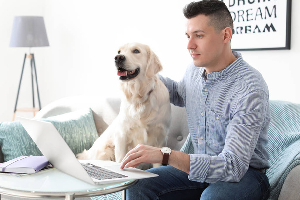 Portrait of owner with his friendly dog using laptop at home - Фото, зображення