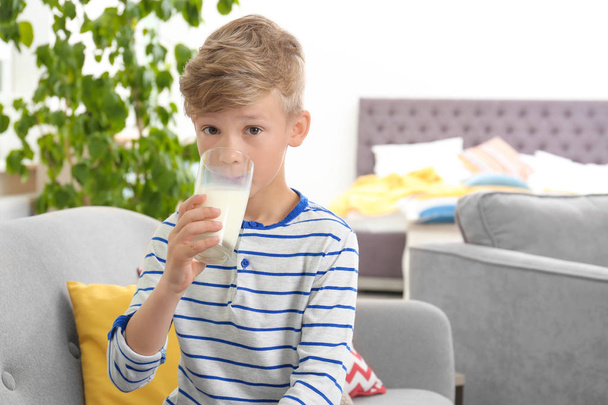 Adorable little boy with glass of milk at home - Foto, Imagen