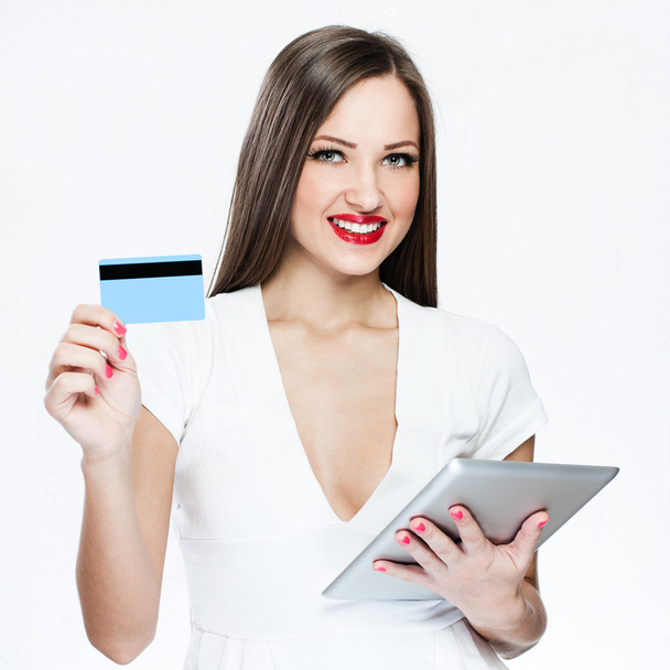 Smiling woman holding credit card and tablet pc - Фото, изображение