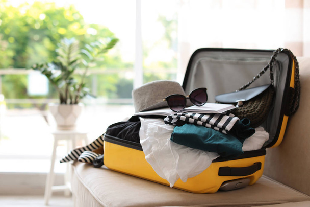 Maleta de color amarillo abierto con diferentes ropas embaladas para el viaje en casa
 - Foto, imagen