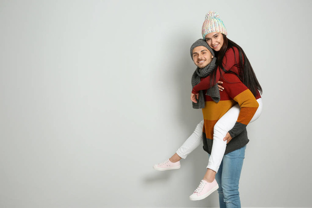 Young happy couple in warm clothes on light background. Christmas celebration - Фото, зображення