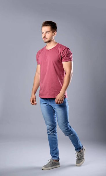 Young man in stylish jeans on grey background - Photo, Image