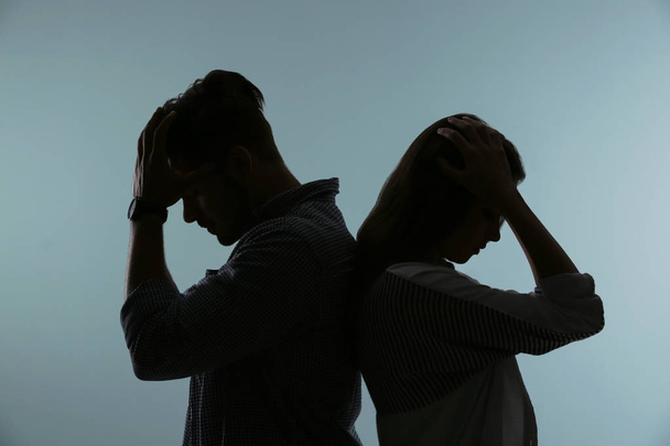 Silhouette of upset couple on color background. Relationship problems - Valokuva, kuva
