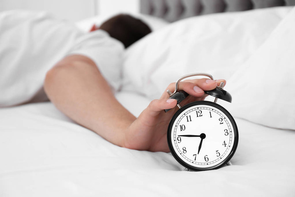 Man turning off alarm clock in bedroom - Photo, image