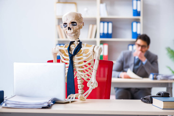Zakenman werkt met skelet in kantoor - Foto, afbeelding