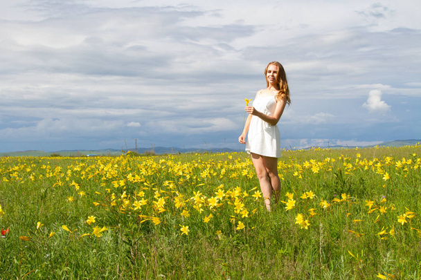a fehér ruha a lány sétál között a vadvirágok - Fotó, kép