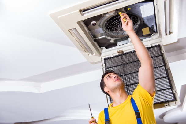 Reparador reparando la unidad de aire acondicionado del techo - Foto, Imagen
