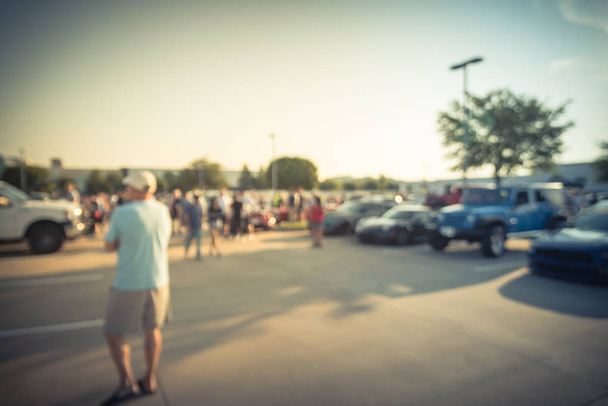 Размытое движение разношерстной группы людей на местном автосалоне в Далласе, штат Техас, США. Занятые люди, просматривающие автомобили всех лет, марок и моделей
. - Фото, изображение