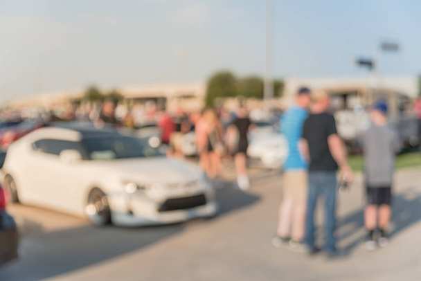 Размытое движение разношерстной группы людей на местном автосалоне в Далласе, штат Техас, США. Занятые люди, просматривающие автомобили всех лет, марок и моделей
. - Фото, изображение