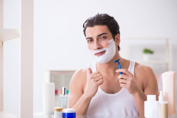 Fiatal jóképű férfi borotválkozik korán reggel otthon. - Fotó, kép