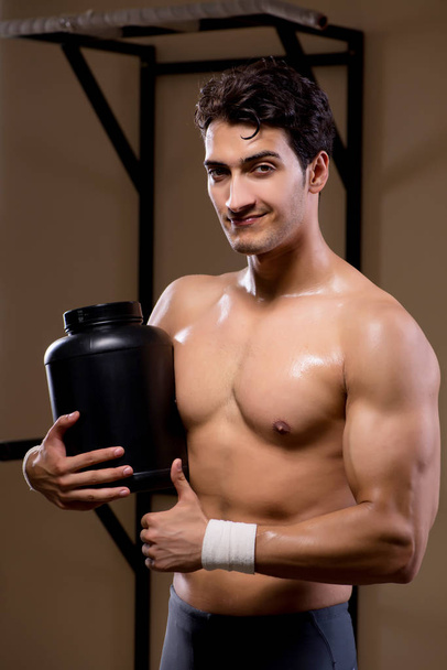 Muž s doplňky živin ve sportovní tělocvičně - Fotografie, Obrázek