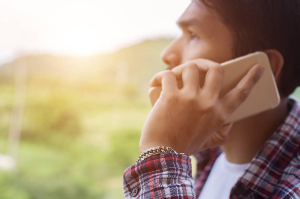 Fiatal csípő szakállas ember beszél telefonon, mosolyogva, kívül hegyre. - Fotó, kép