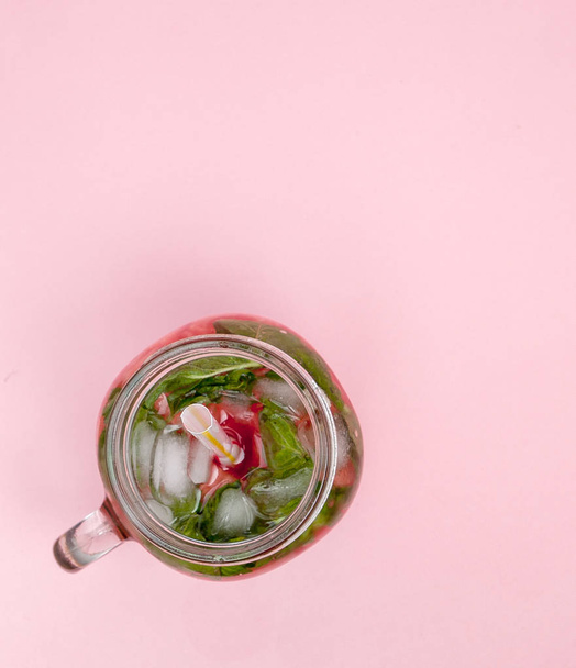 Jar of cold fresh lemonade with piece of watermelon and ice on pink background. - Foto, Bild
